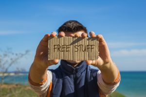 man holding up cardboard sign that reads "free stuff"