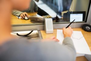 customer with pen and paper writing application at bank office