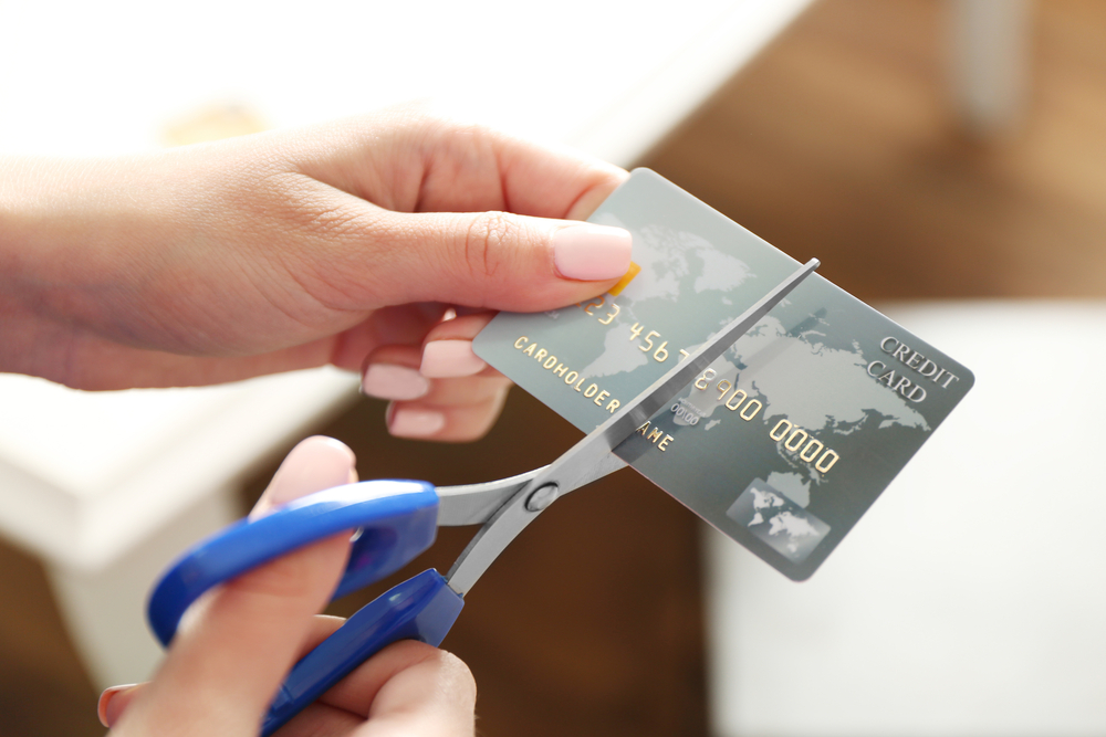 image of female hands holding scissors to cut credit card
