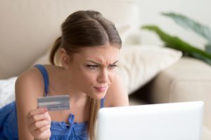  woman holding credit card and looking at laptop