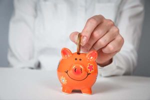 Orange piggy bank with man putting coin inside