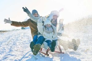 Family driving sled on snow having fun in winter