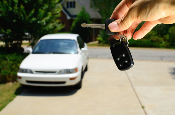 hand holding keys with used car in background, out of focus